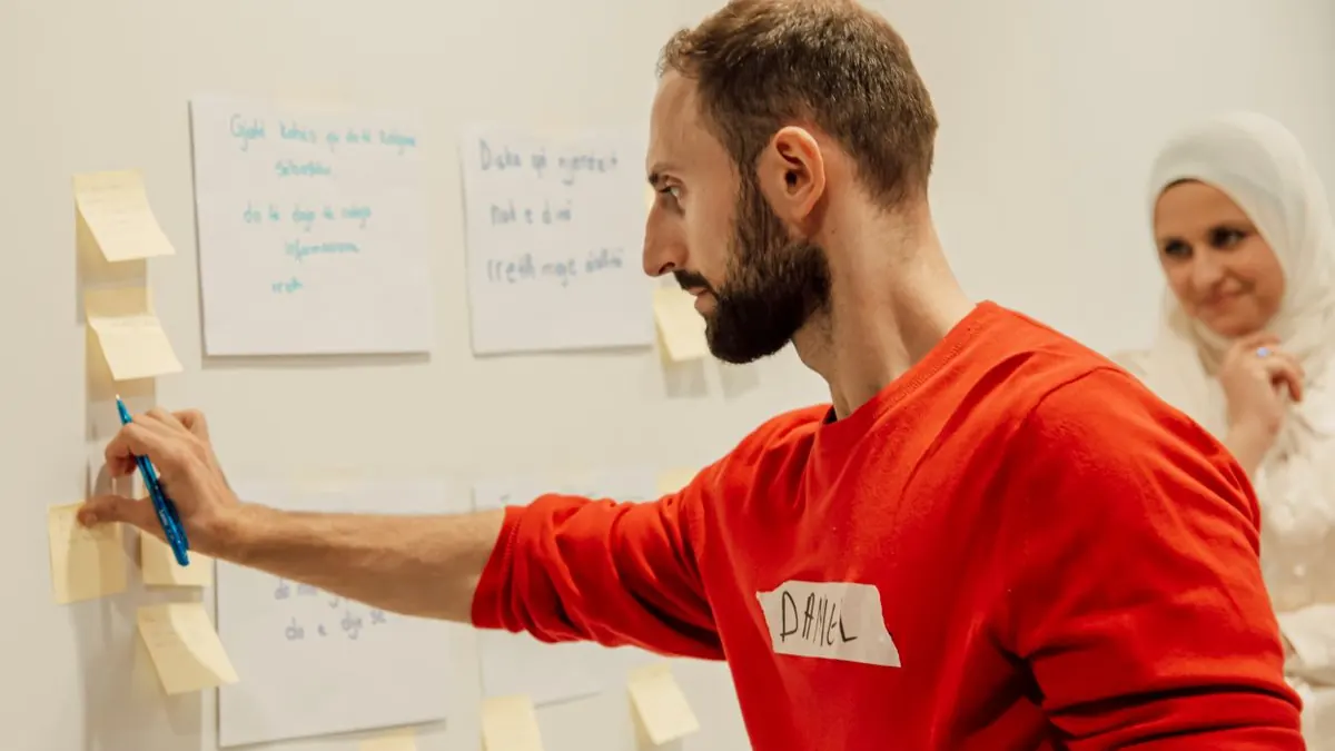 Muž lepí lepicí lístek na tabuli během workshopu