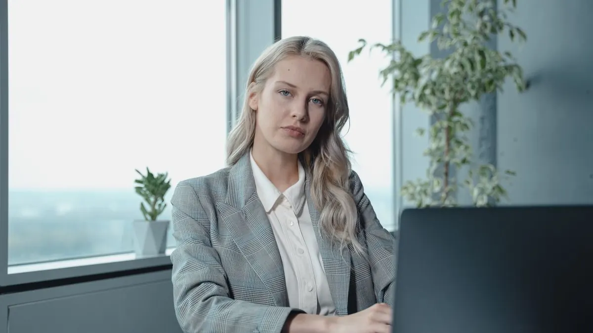 Blondýna sedí u stolu v moderní kanceláři u okna