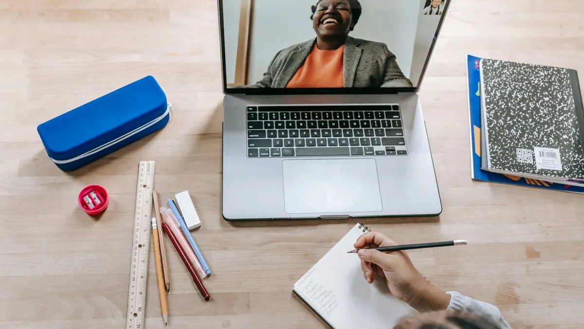 Videohovor s lektorem na obrazovce notebooku, ruka píše poznámky