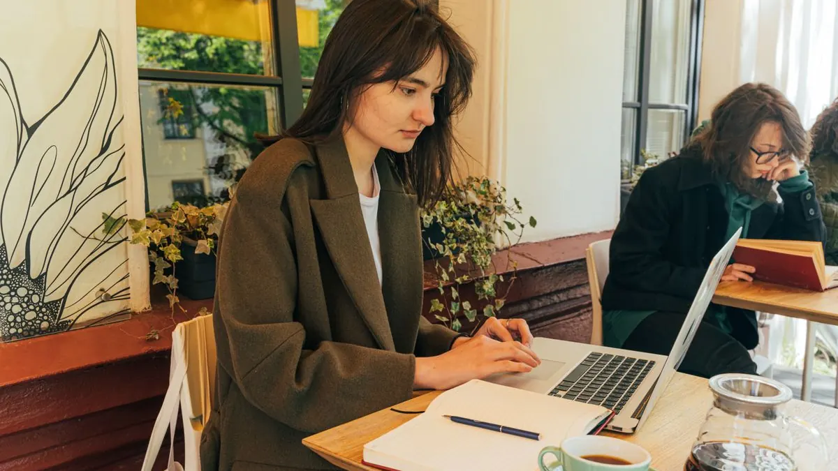 žena pracuje s notebookem a zápisníkem v kavárně